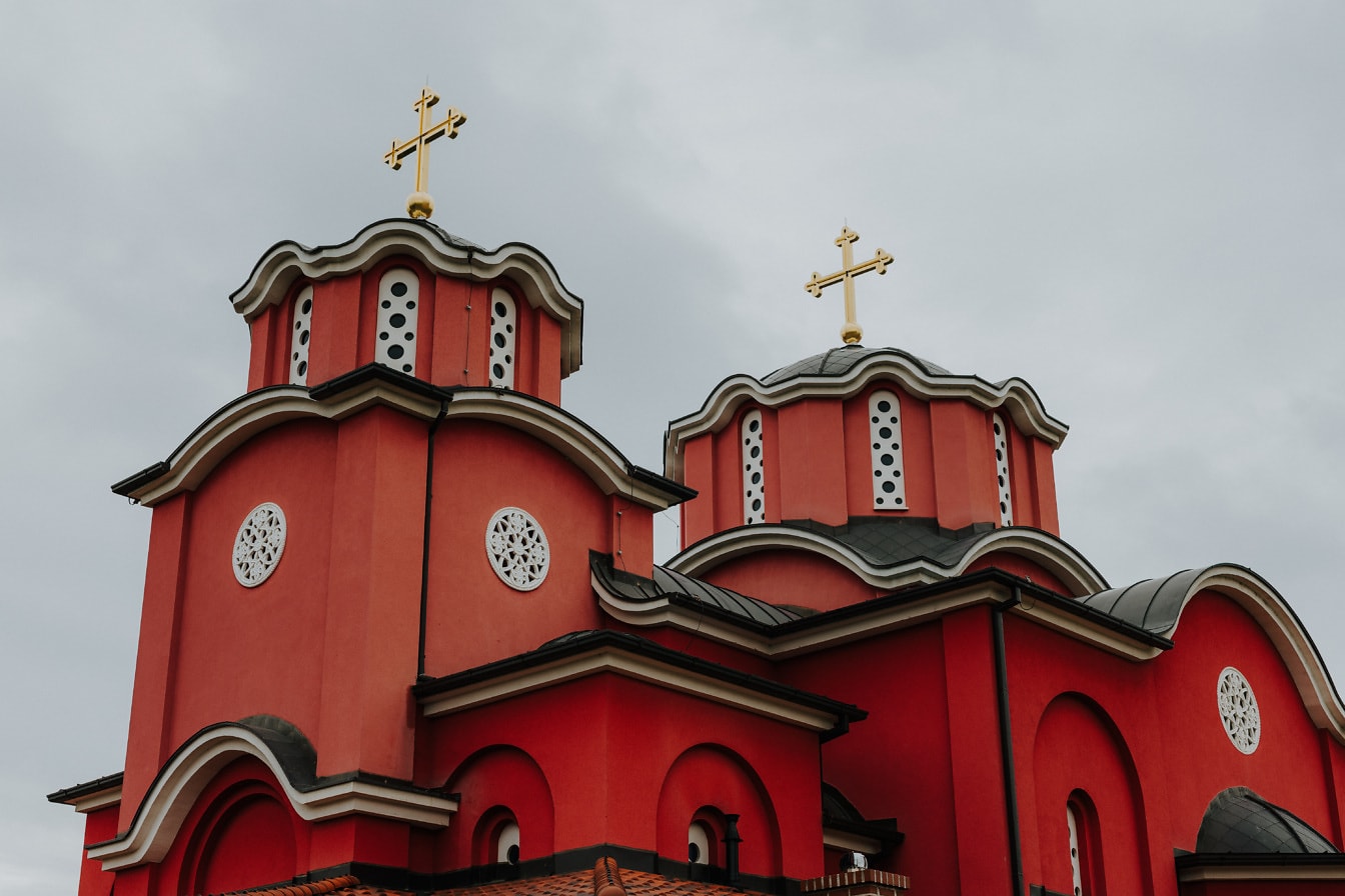 Σκούρο κόκκινο ορθόδοξο μοναστήρι με χρυσό σταυρό στον τρούλο