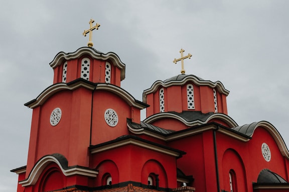 Dark red orthodox monastery with golden cross on dome