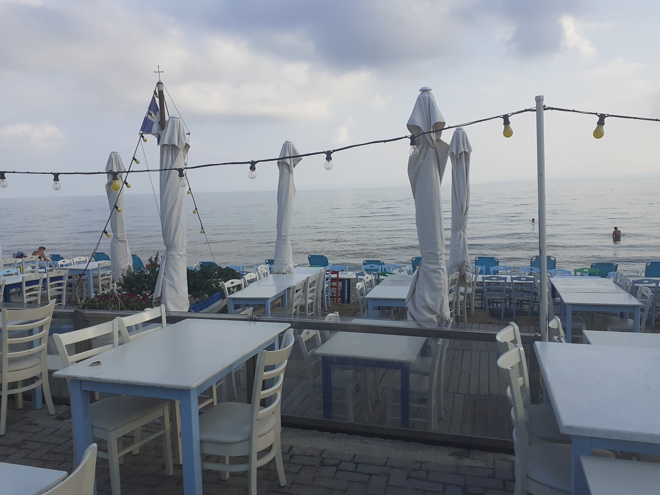 Terraço vazio do restaurante à beira-mar com cadeiras e mesas brancas