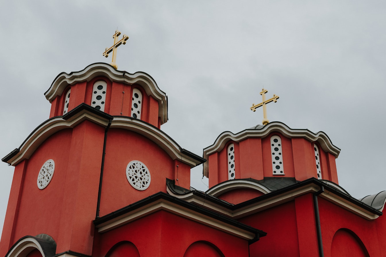 Dark red orthodox monastery with golden cross on rooftop