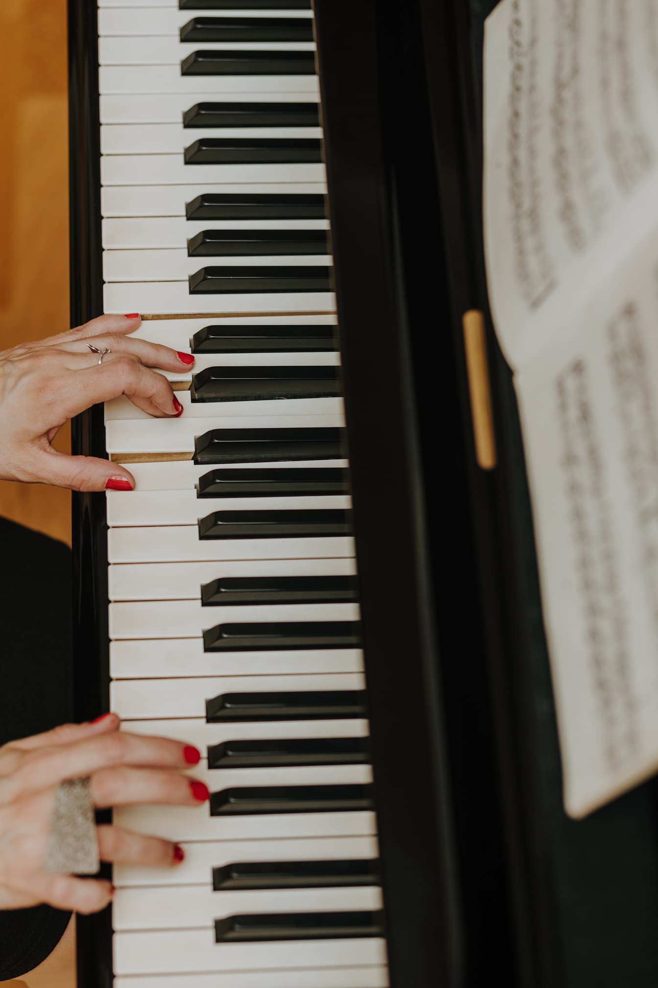 Detailný záber rúk klaviristu hrajúceho klasickú hudbu na klavíri