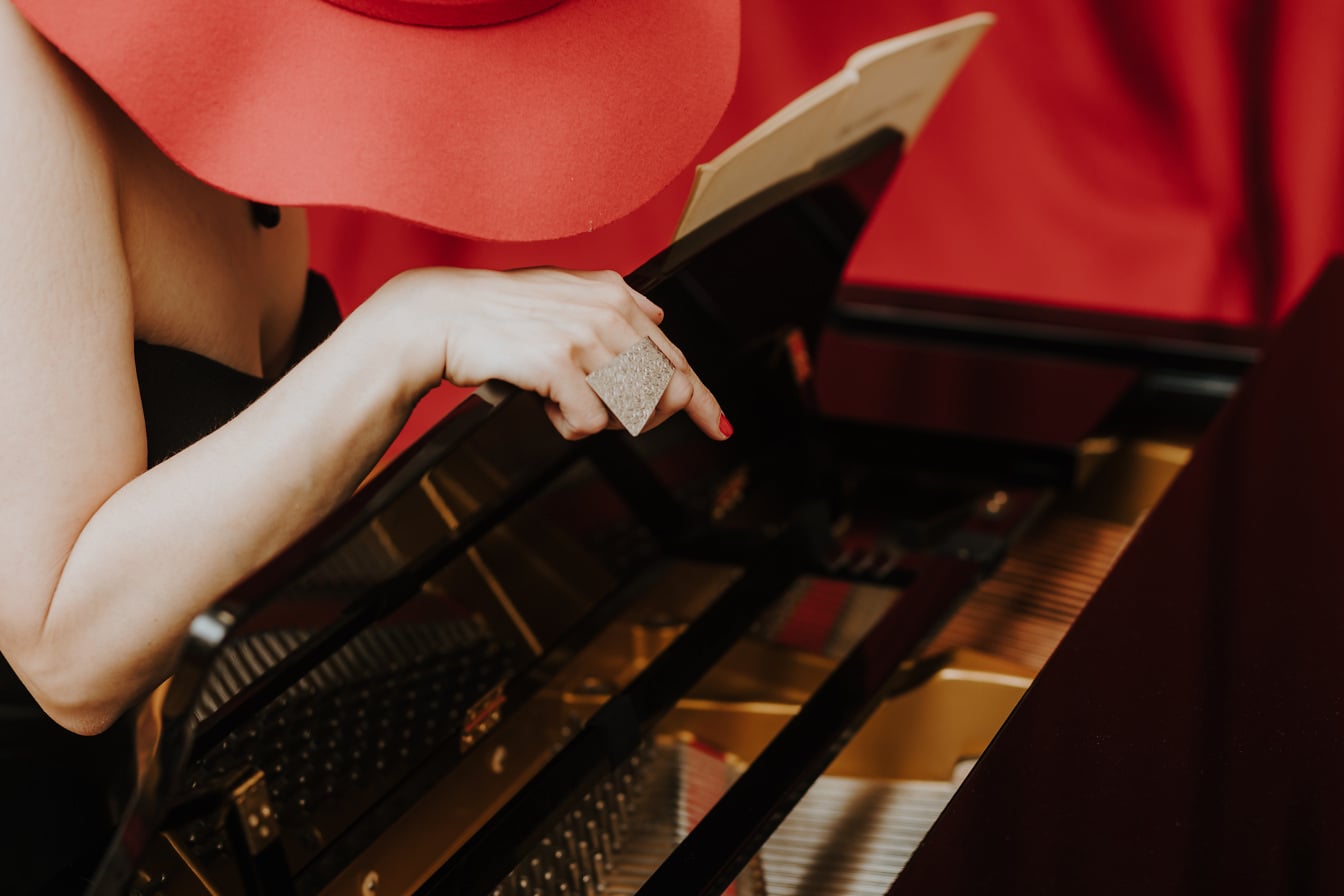 De pianist van de vrouw met rode hitte die pianomuziekinstrument speelt