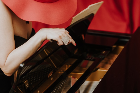 Woman pianist with red heat playing piano music instrument