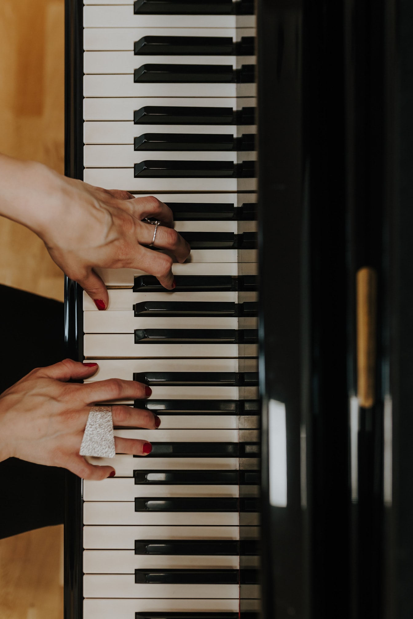 ภาพระยะใกล้ของมือของนักเปียโนหญิงที่เล่นเครื่องดนตรีเปียโน