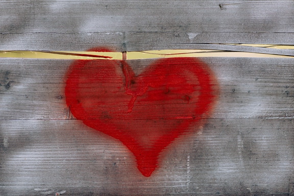 Pintura en aerosol de color rojo oscuro en forma de corazón sobre tablones de madera