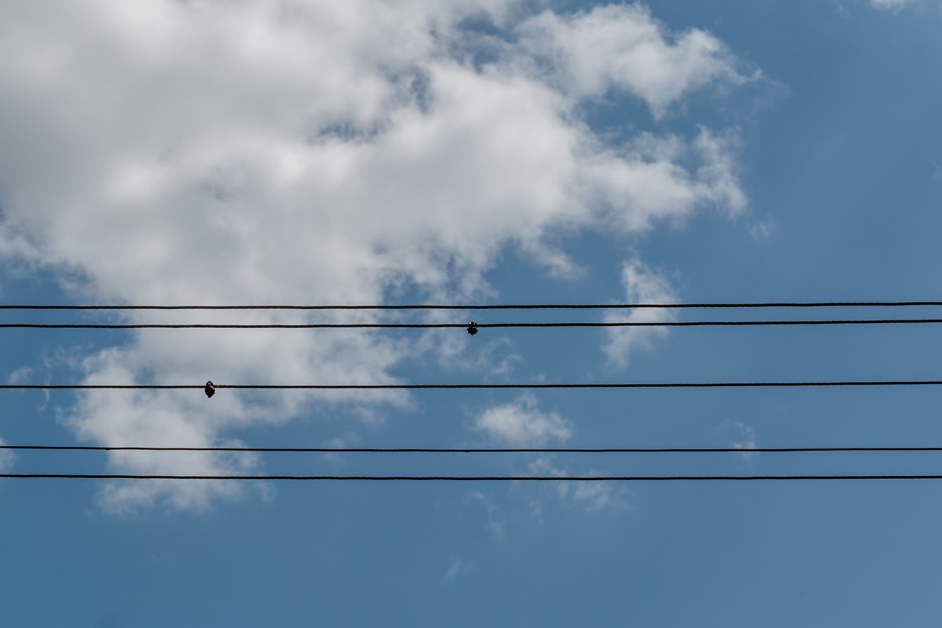 Horizontal electric wires on blue sky with clouds