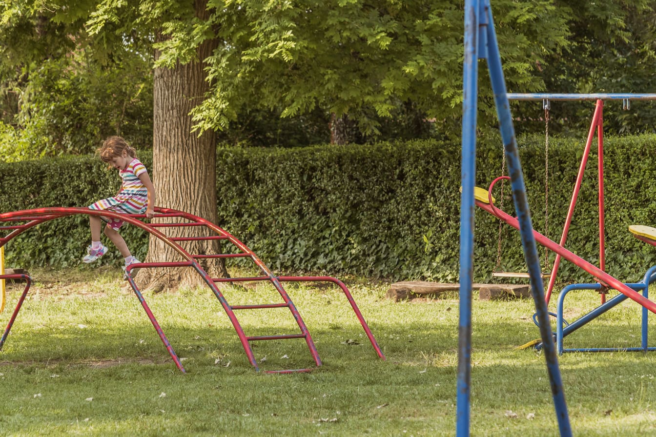 Małe dziecko w wieku szkolnym bawi się na placu zabaw na świeżym powietrzu