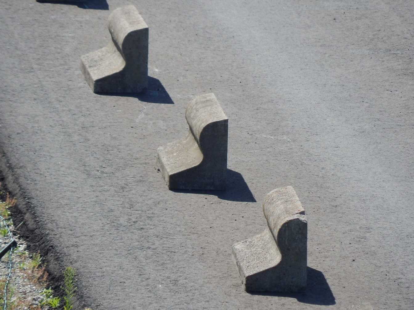Bloques de forma distorsionada de hormigón gris en carretera asfaltada