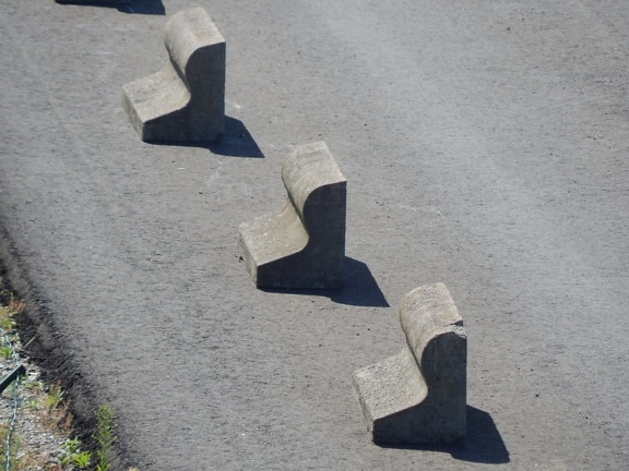 Grey concrete distorted shape blocks on asphalt road