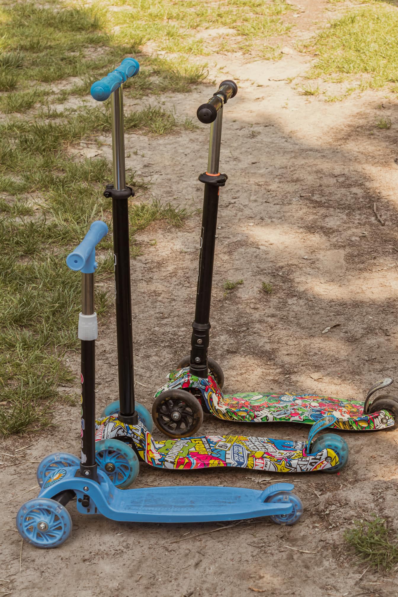 Trei jucării trotinetă colorate în prim-plan la sol