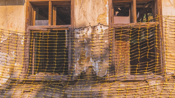 木製の窓と朽ち果てたファサードのある廃墟の家