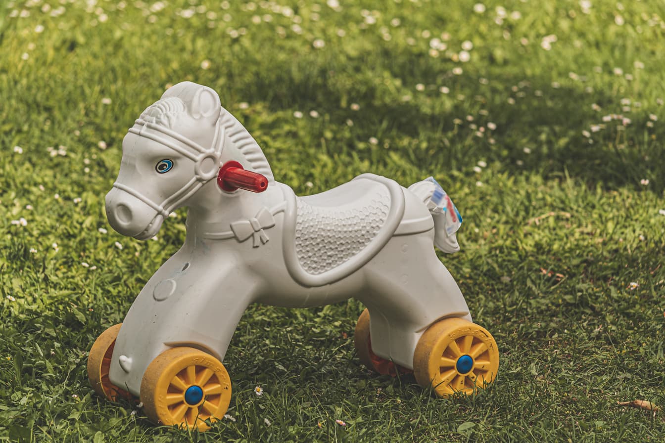 Mainan plastik kuda putih di halaman rumput hijau