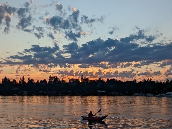 Silhouette of canoe on lake in sunrise