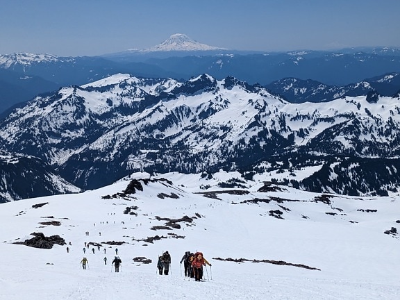 Mountain climber skiers climbing on snowy mountain peak