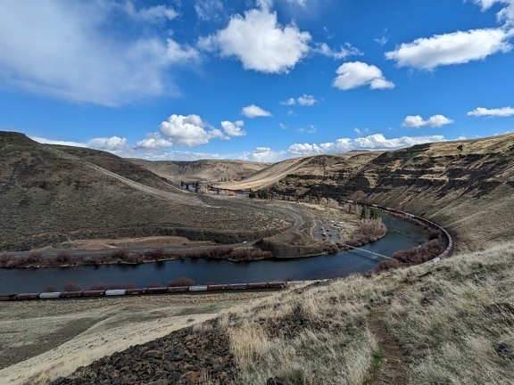 River in desert with railroad with train