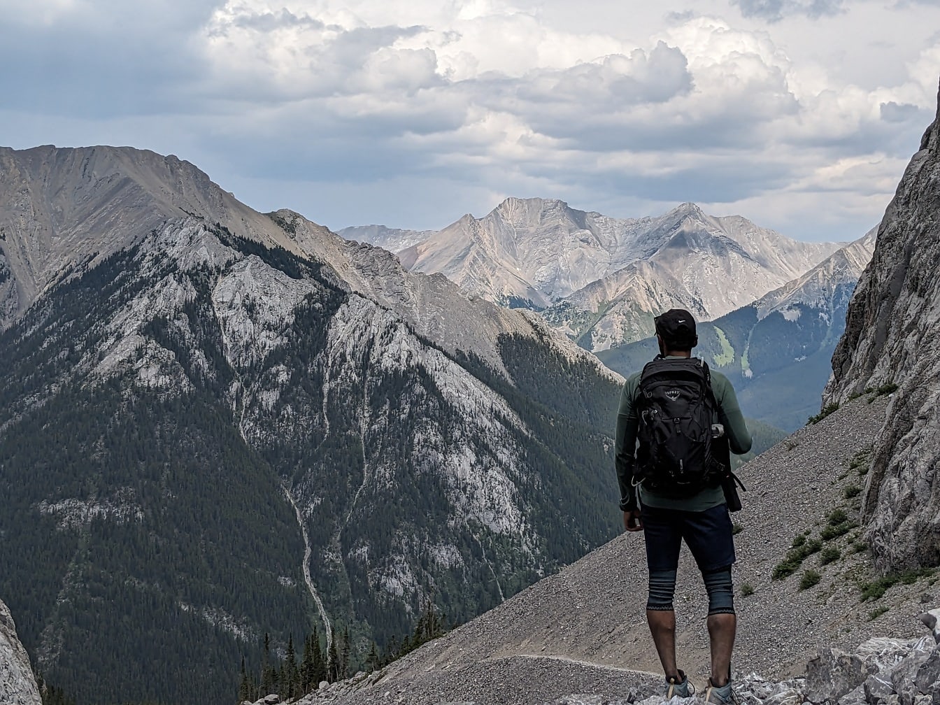 Turista s batohom na vrchole hory a pozorovanie panorámy hôr