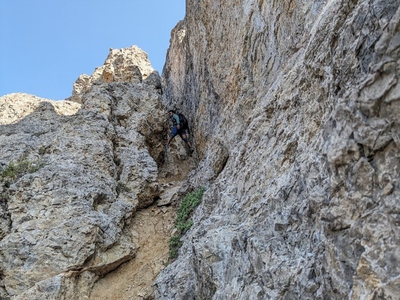 Alpinist mountain climber climbing on narrow cliffs