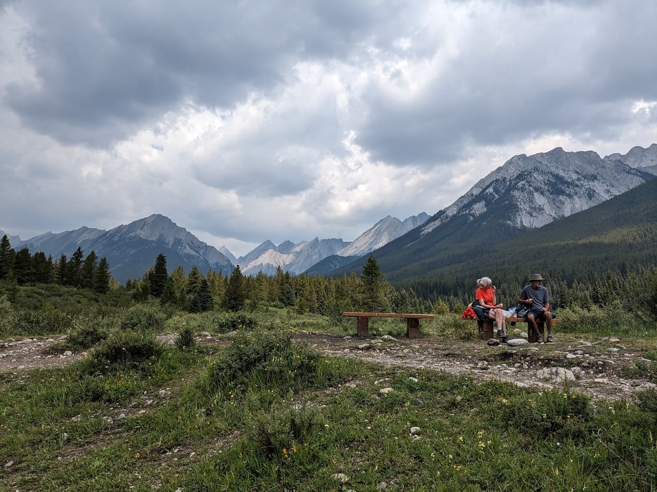 Turisté sedící na lavičce v horách kanadského národního parku