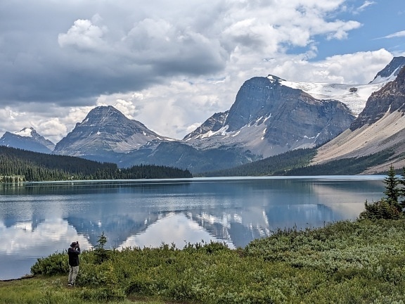 Osoba fotografující majestátní panorama jezera