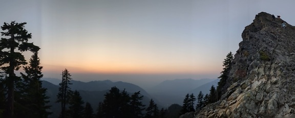 Mountain climbers climbing at cliff in twilight