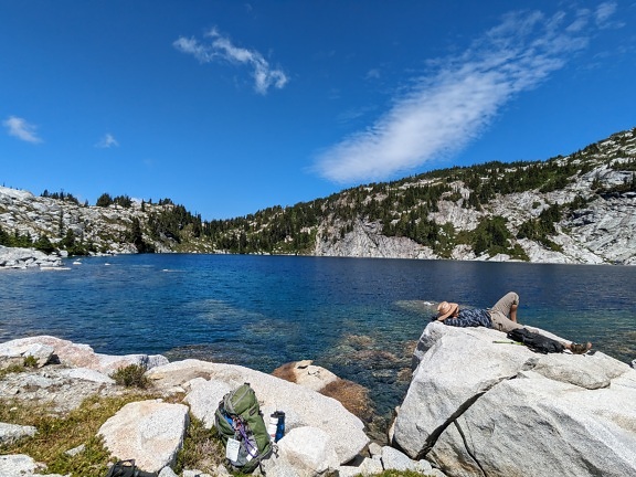 Hiker relaxing on rocks on lakeside majestic panorama landscape