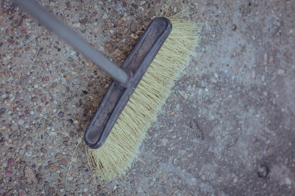 Close-up of old plastic broom tool on concrete