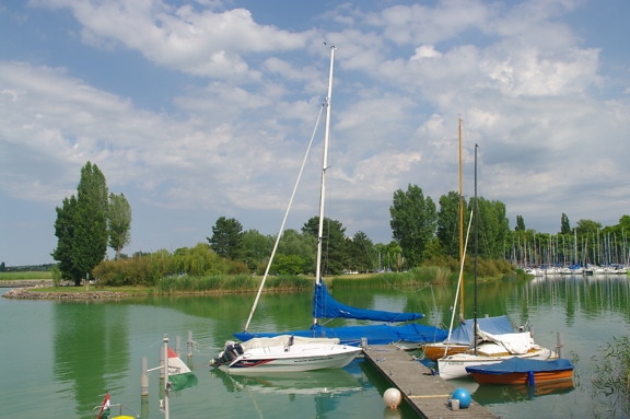 Small yachts on wooden pier at calm lake