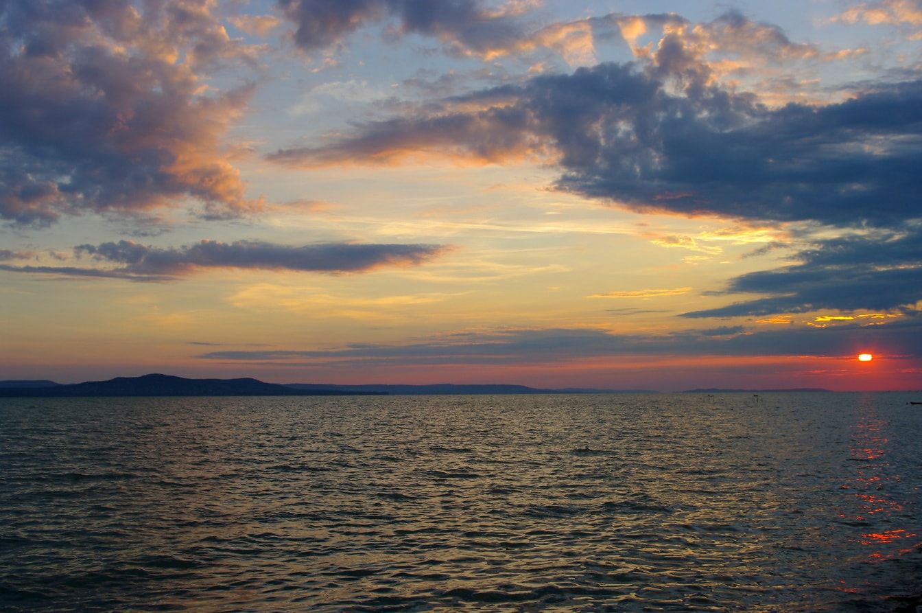 Majestátny východ slnka nad jazerom Balaton v Maďarsku so zamračenou oblohou