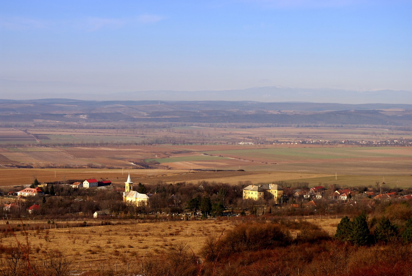 Pemandangan panorama ladang pedesaan dan pemukiman dari lereng bukit