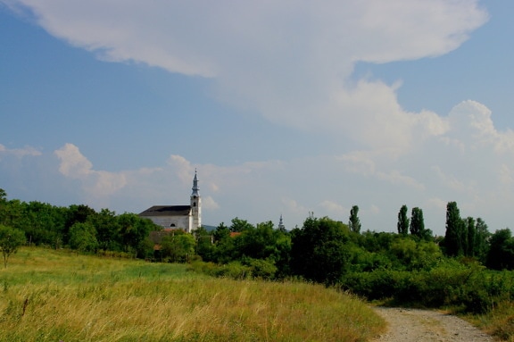 Schmutzige Straße auf dem Land mit Kirchturm im Hintergrund