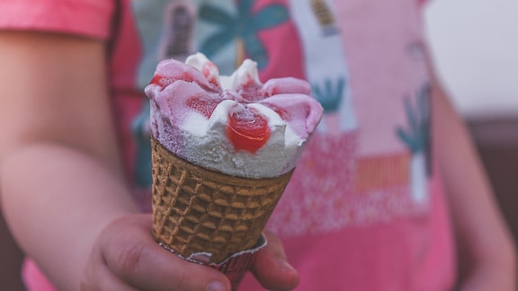 Child holding strawberry ice-cream cornet close-up