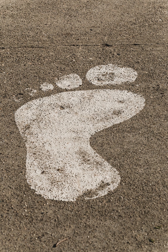 Kaba beton üzerindeki beyaz boya ayak izi işaretinin yakın çekimi