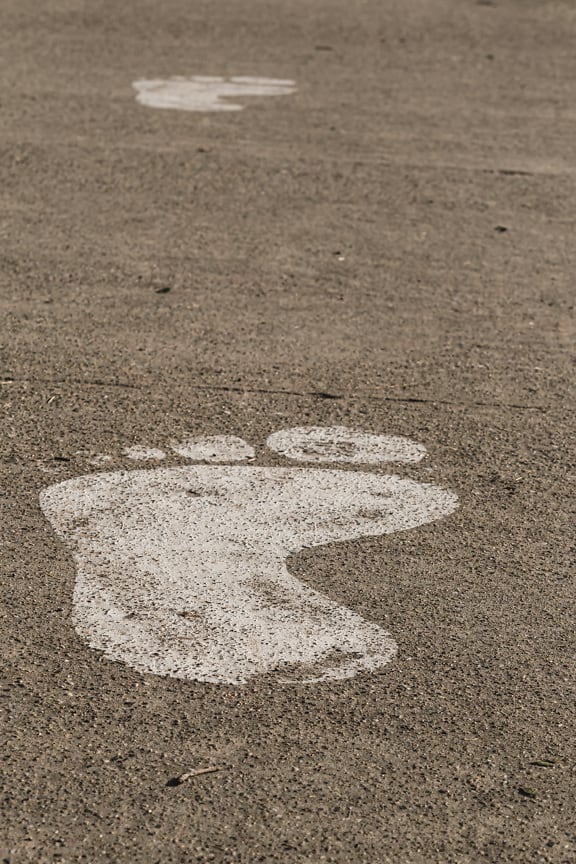 White paint footprint sign on concrete walkway