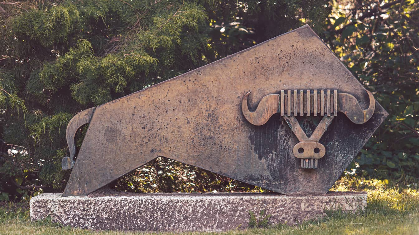 Rzeźba z brązu przedstawiająca byka na granitowym bloku w parku