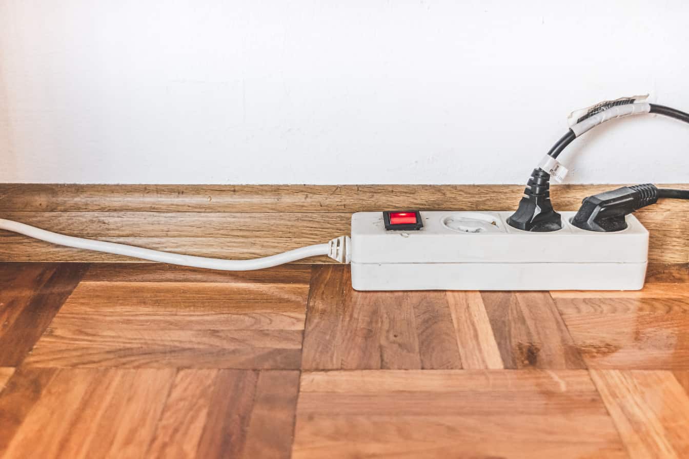 Electric cord with socket for extension cable on parquet floor