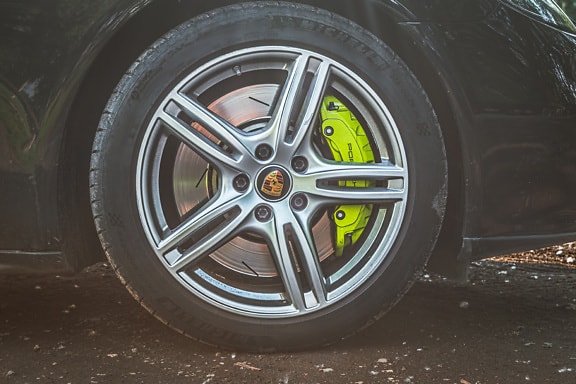 Primer plano de la rueda de aluminio del coche Porsche con rotura amarilla verdosa