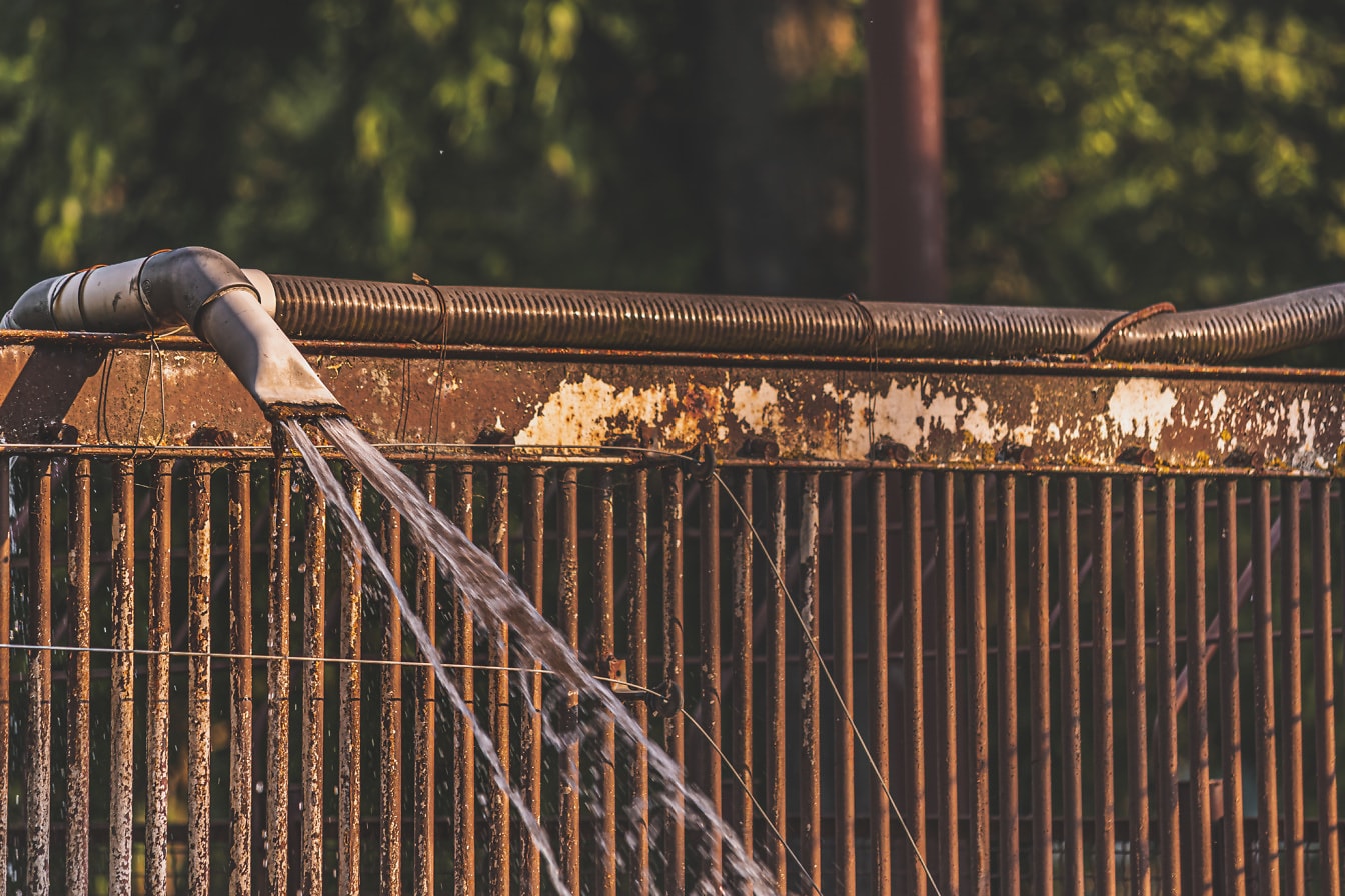 Paslı metal dökme demir çit üzerinde su borusu