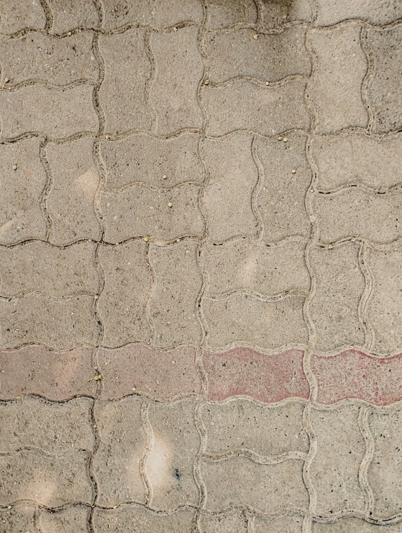 Detailný záber betónovej dlažby s tmavočervenou čiarou