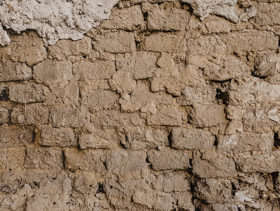 Grunge suchá zeď z nepálených cihel s texturou bláta zblízka