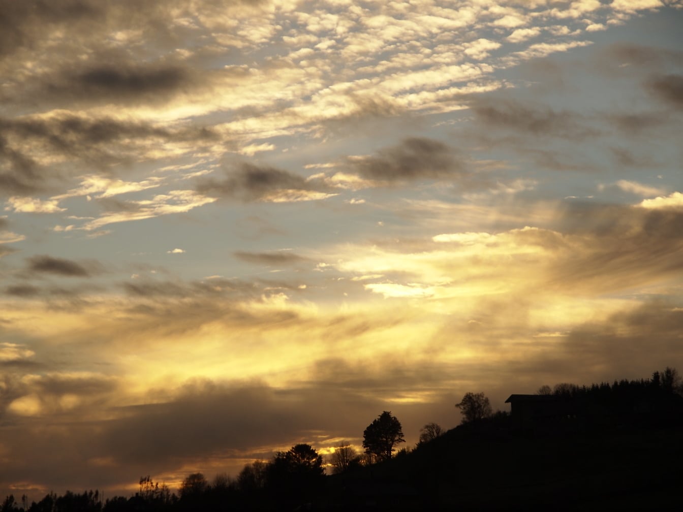 Na zonsondergangsilhouet van heuveltop met gelige hemel