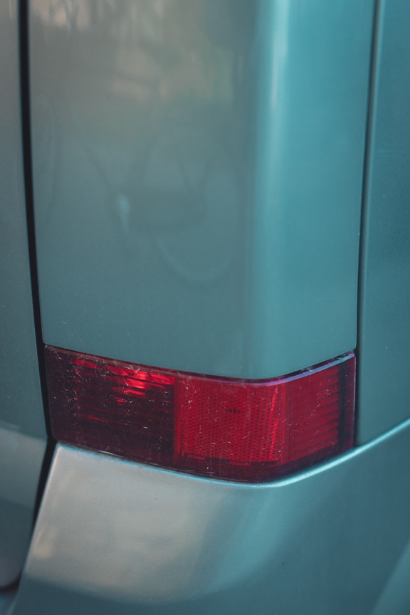 Close-up detail of bumper with rear dark red light of car
