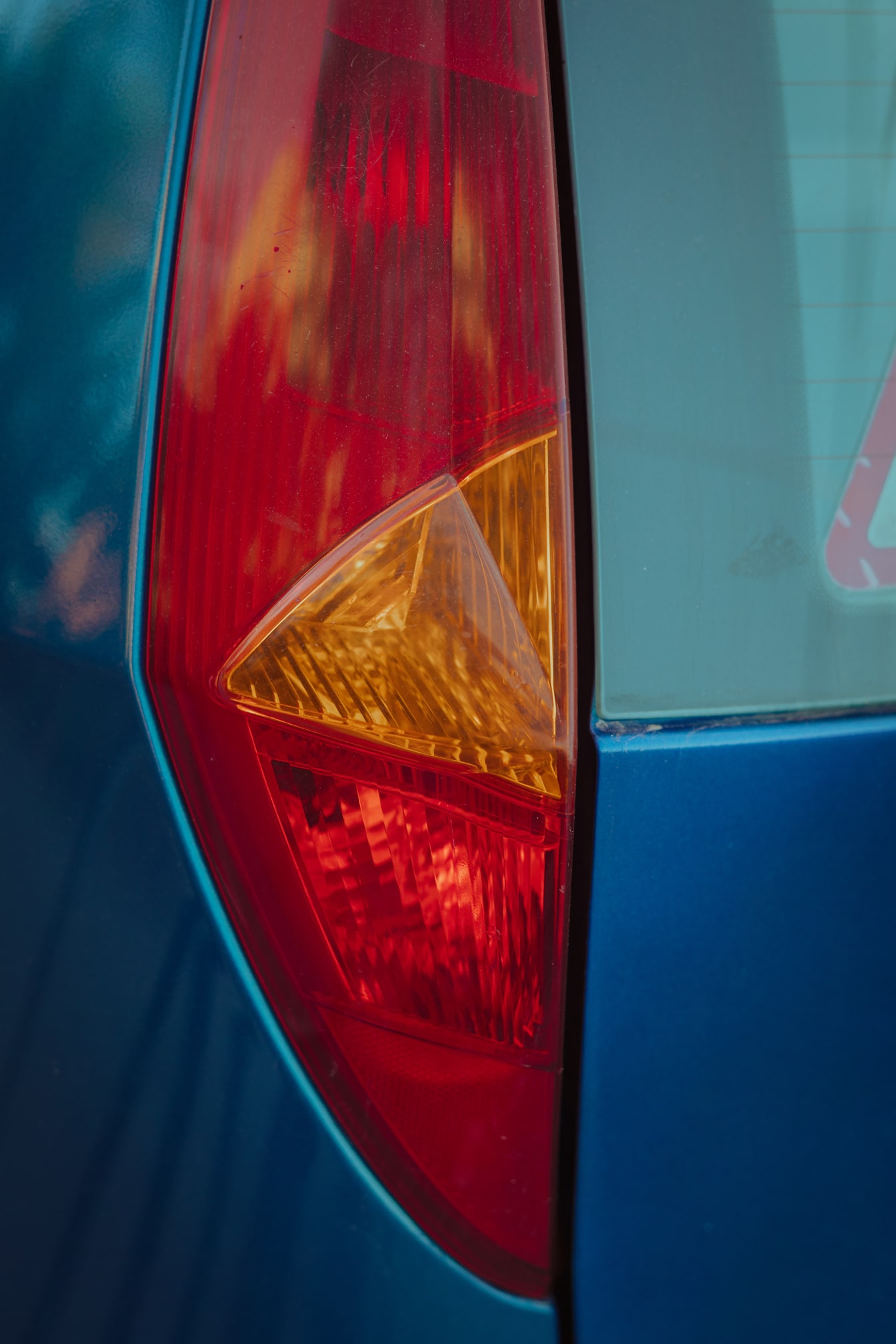 Närbild av mörkröd och orange gul plastdetalj av bilen