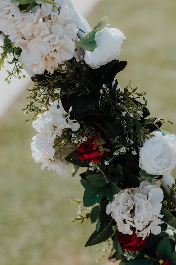 Close-up detail of white flowers and dark red roses in bouquet