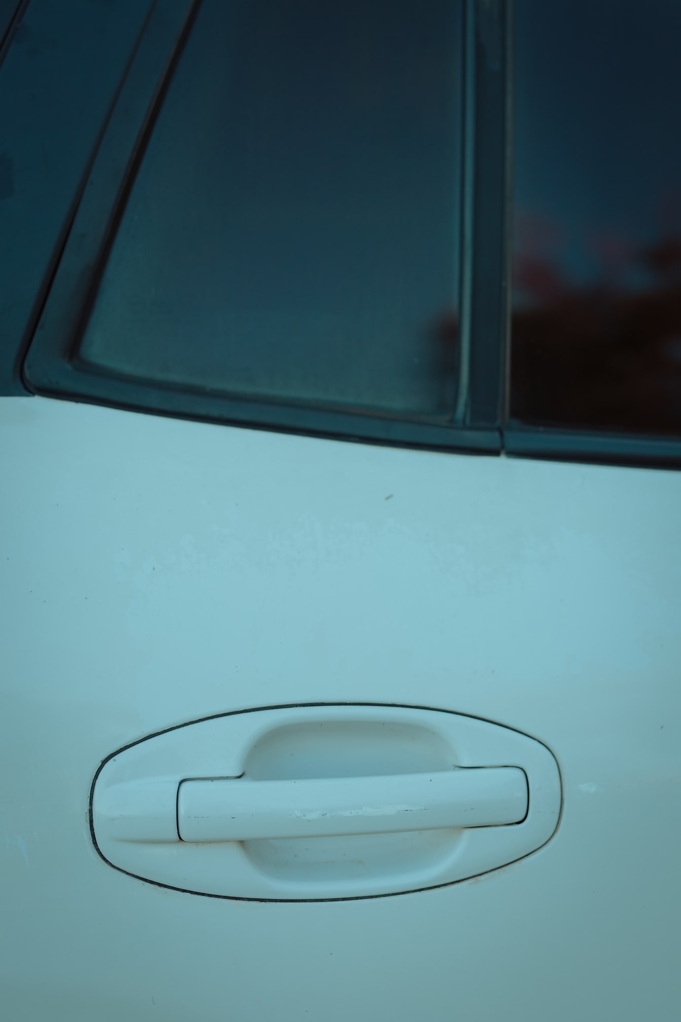 Detaliu de prim-plan al mânerului ușii de pe mașina metalică albă