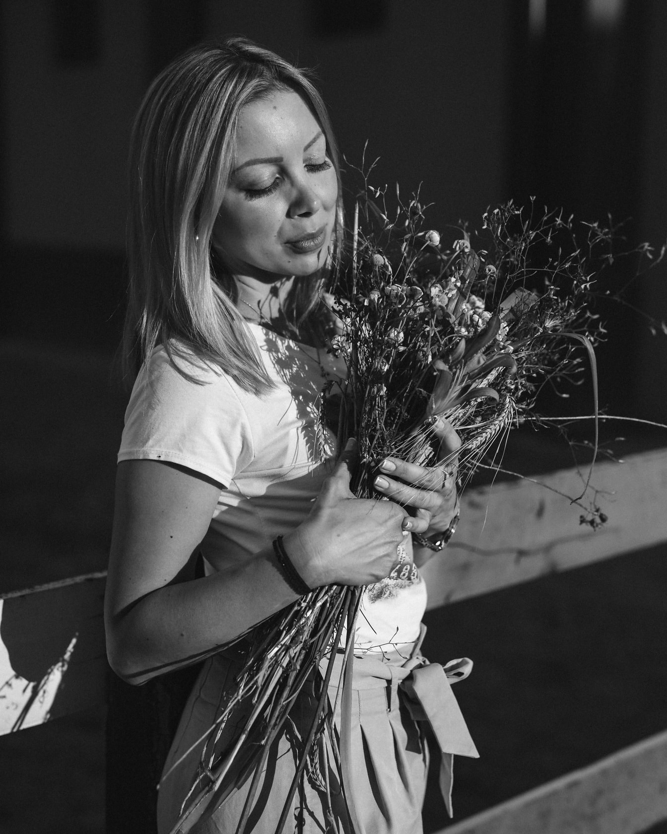 Monochrome photograph of young women holding bouquet of dry flowers