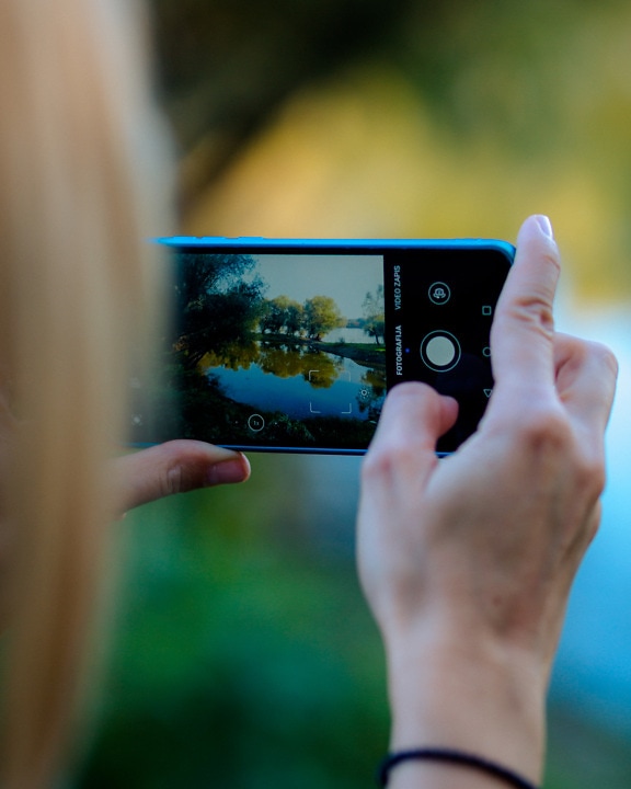 Prim-plan cu telefonul mobil în mâinile unui fotograf peisagist