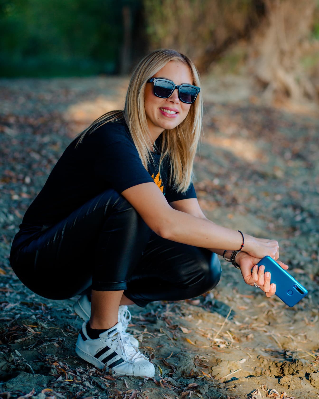 Rozkošné blond vlasy mladá žena se slunečními brýlemi a mobilním telefonem
