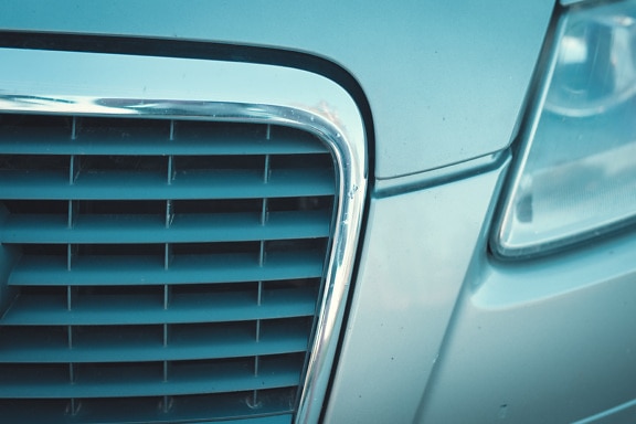 Metallic sedan car headlight and grille close-up detail