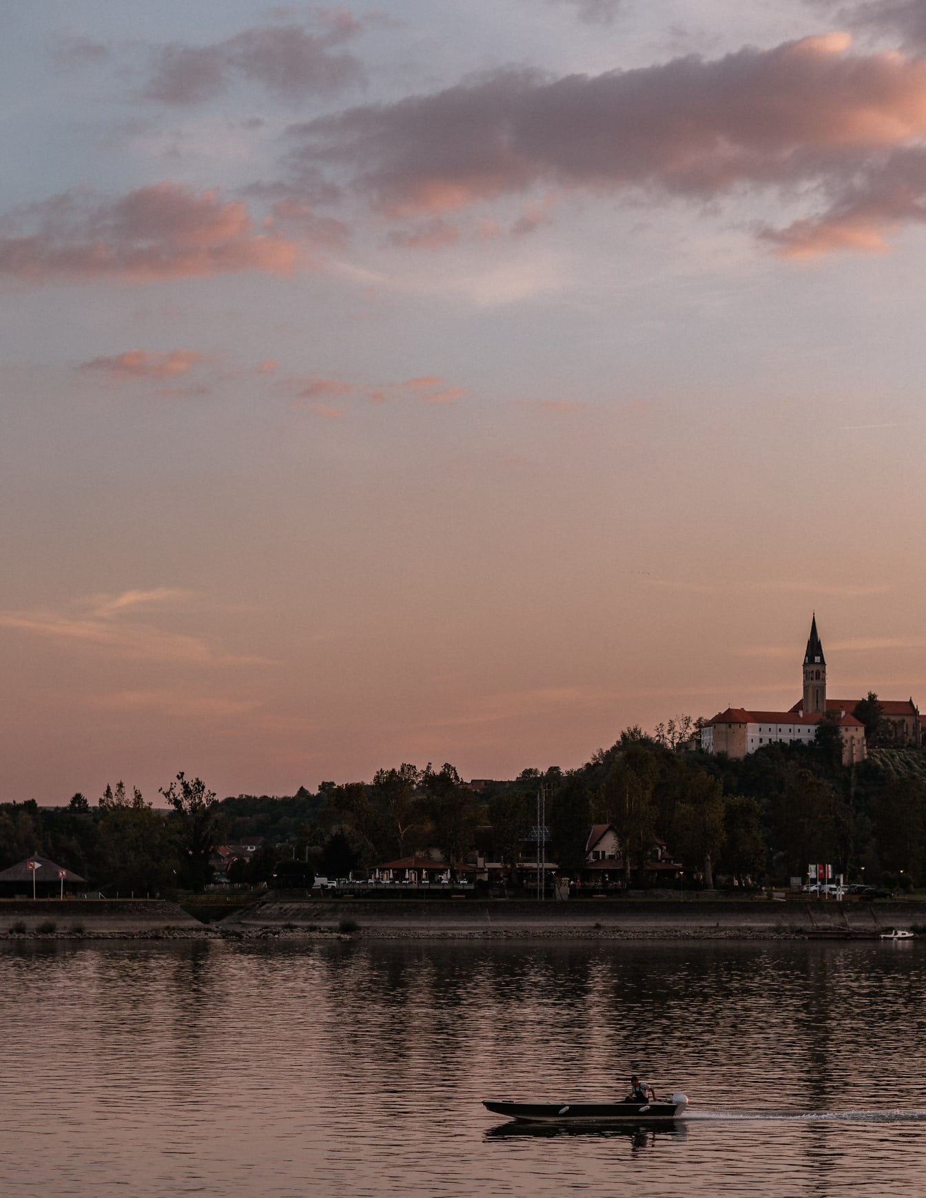 Здрач небе над църковна кула на брега на река Дунав