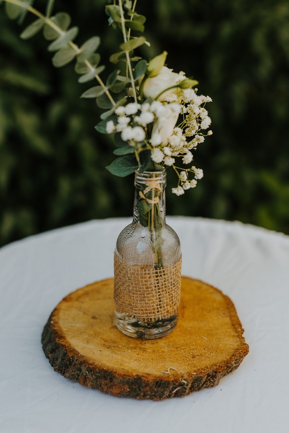 White flowers in transparent bottle rustic decoration on table close-up
